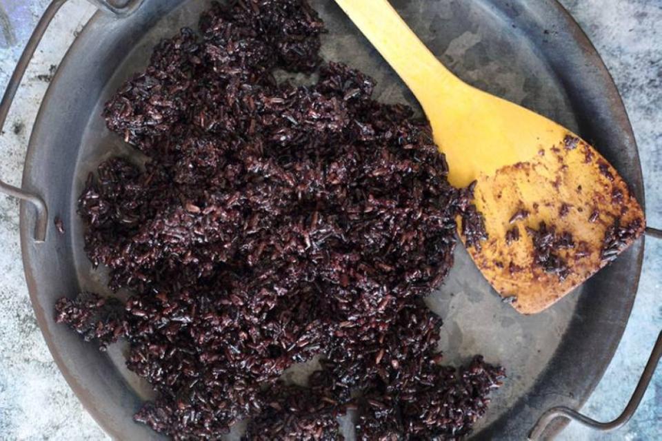 Spreading out cooked black glutinous rice to cool.