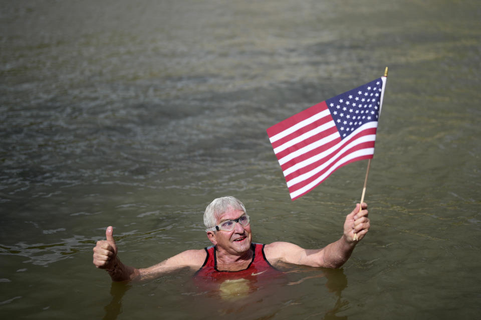 Joel Stratte-McClure, 75, of the US, holds American flag after completing a short swim in the Seine river, Thursday, July 4, 2024 in Paris. The Seine River has been found unsafe according to test results published last Friday, less than a month before the Paris Olympics. (AP Photo/Thibault Camus)