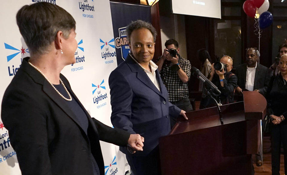 Chicago Mayor Lori Lightfoot, at podium, holds hands with her spouse, Amy Eshleman, as she concedes the election in the mayoral race, Tuesday, Feb. 28, 2023, in Chicago. (AP Photo/Charles Rex Arbogast)