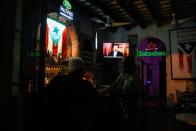 People watch a television broadcast of Puerto Rico's governor Ricardo Rossello's speech at a bar in San Juan