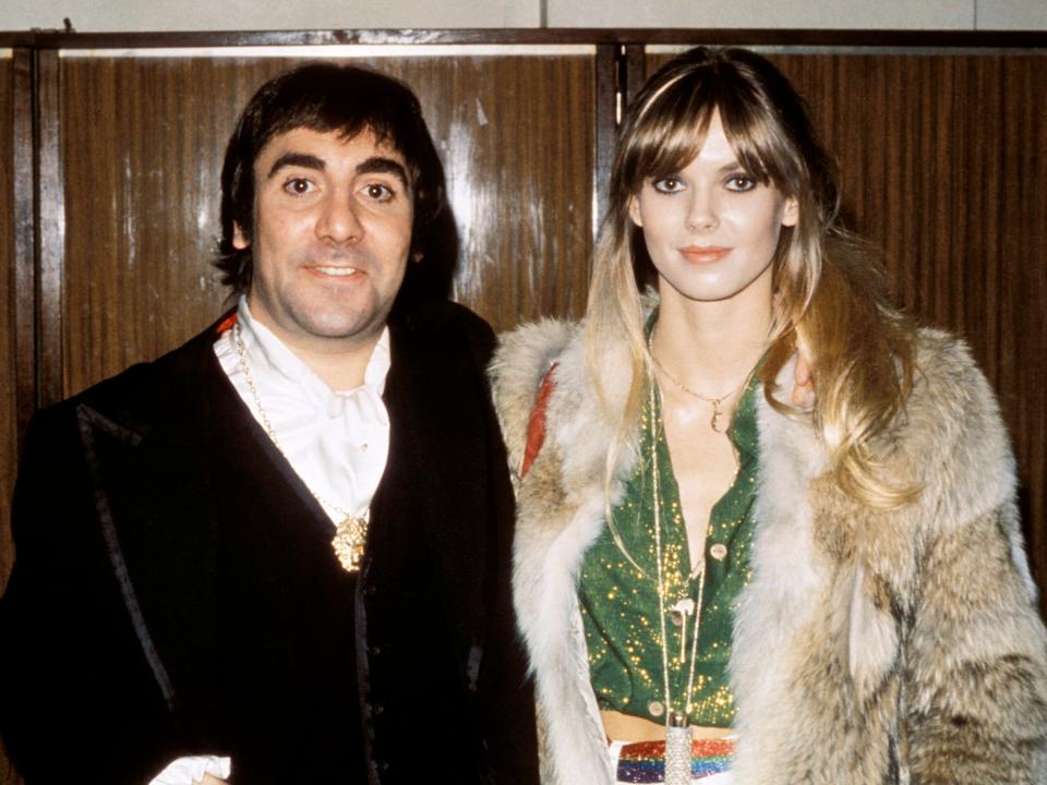 Keith smiling in a suit and Anette smiling in a fur coat and green dress.