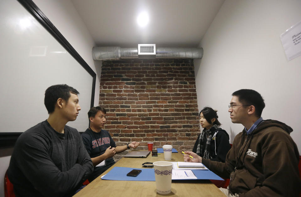 In this Saturday, Feb. 8, 2014 photo, participants Ian Wong, from left, Willy Chu, Yuriko Tamura and Steve Nguyen meet during a coding and team formation session at FinCapDev San Francisco Hackathon in San Francisco. A record 1,500 hackathons around the world are planned for this year, up from just a few dozen in 2010, and their focus is broadening from developing lucrative apps to solving problems with coding for an array of issues including dental, fashion, immigration, transgender and social justice. (AP Photo/Jeff Chiu)