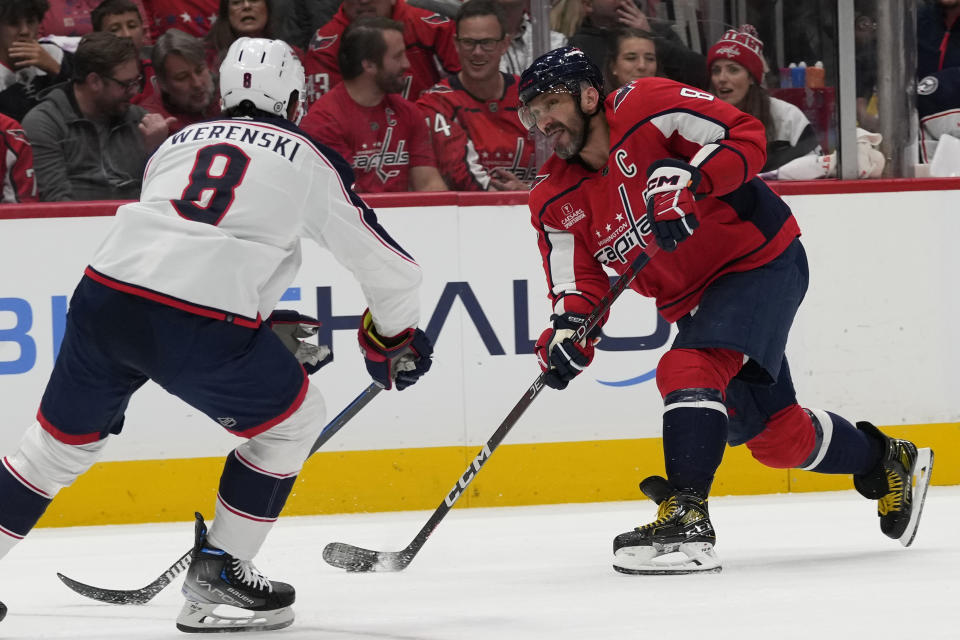 Washington Capitals left wing Alex Ovechkin (8) shoots the puck around Columbus Blue Jackets defenseman Zach Werenski (8) during the first period of an NHL hockey game in Washington, Saturday, Nov. 18, 2023. (AP Photo/Susan Walsh)