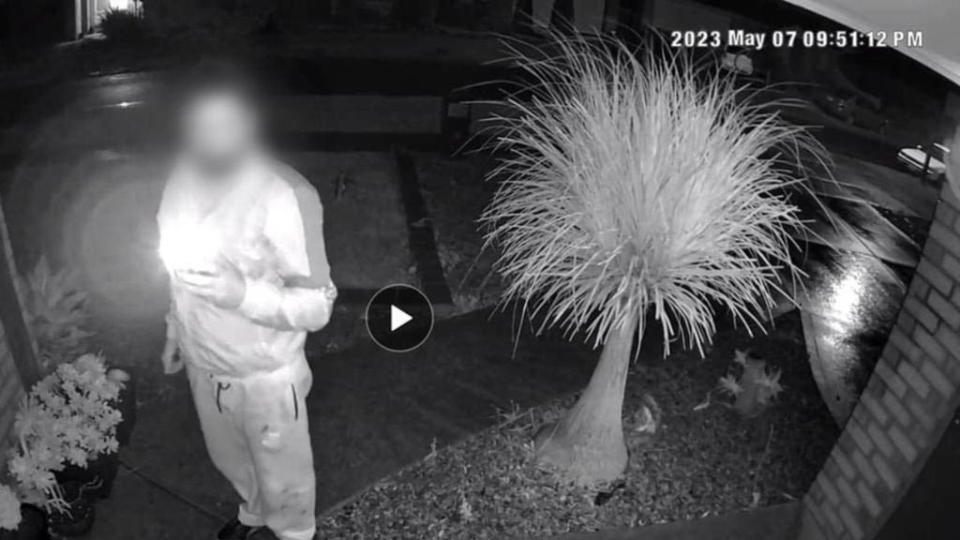 A black and white CCTV image shows an UberEats driver standing at the front door of a home in Wyndham Vale, Melbourne.