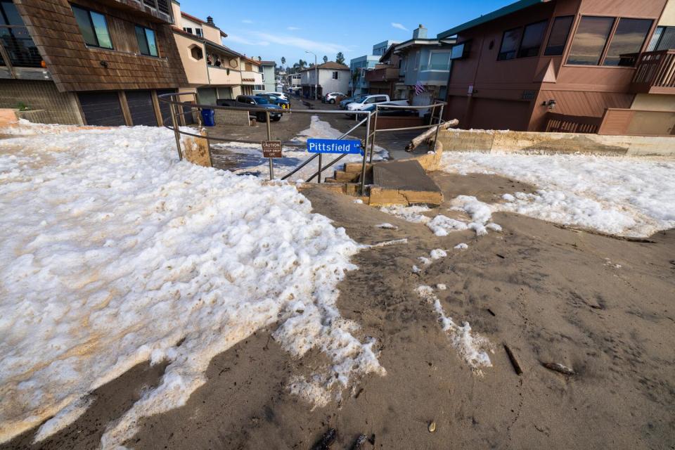 Sand, water and foam inundated Pittsfield Lane after a seawall and sand berm was breached in Ventura.