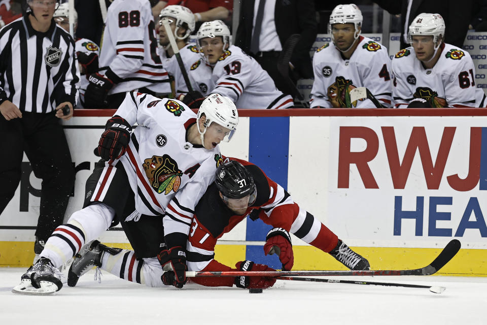 Chicago Blackhawks defenseman Connor Murphy (5) and New Jersey Devils center Pavel Zacha (37) battle for the puck during the first period of an NHL hockey game Friday, Oct. 15, 2021, in Newark, N.J. (AP Photo/Adam Hunger)