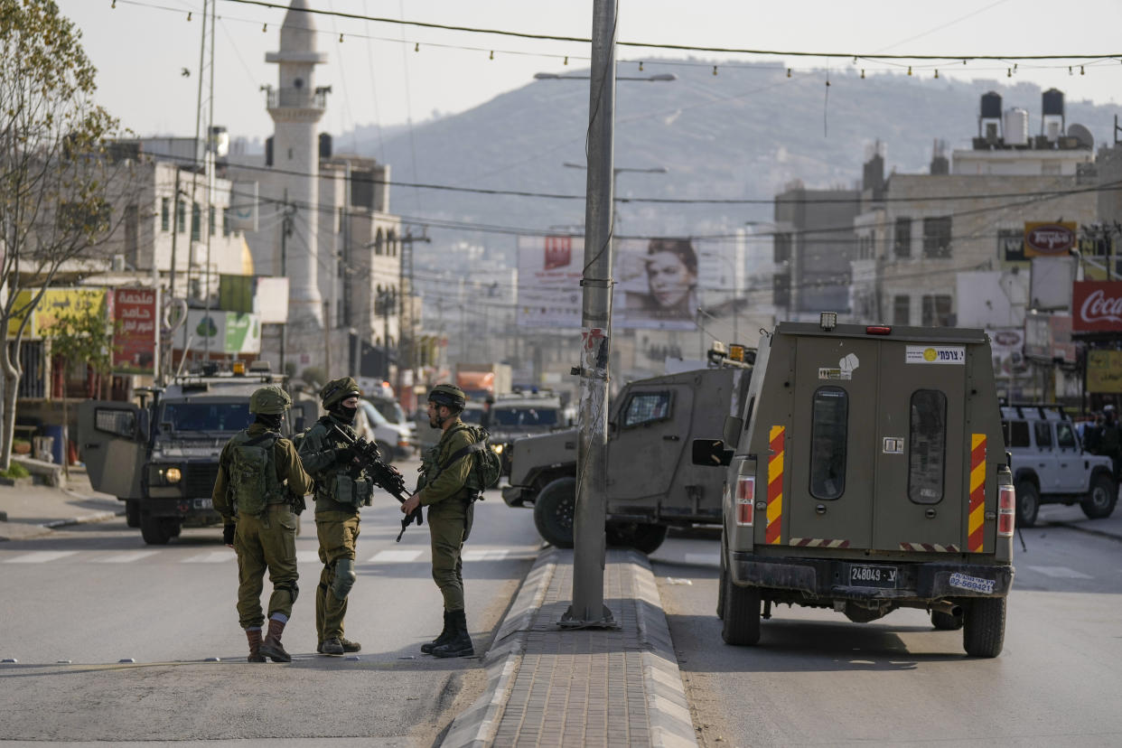 Israeli soldiers take up positions at the scene of a Palestinian shooting attack on an Israeli car at the Hawara checkpoint, near the West Bank city of Nablus, Sunday, Feb. 26, 2023. Two Israelis were killed in the shooting, Israeli officials said. (AP Photo/Majdi Mohammed)