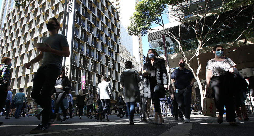 A photo of a Brisbane street in the city showing people walking and wearing masks.