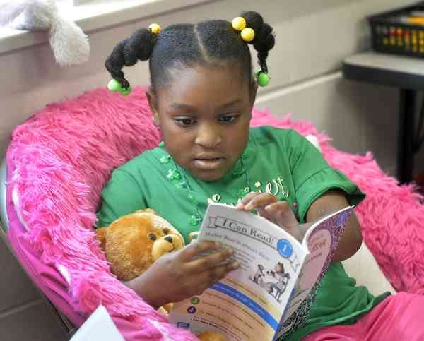 First grader Chelsea Page at May Howard Elementary School holds her teddy bear and reads her new book. The bear and book were gifts of Bess Butler and her grandfather Lee Butler who were at the school as part of the Rotary Read-In project. [Steve Bisson/savannahnow.com]