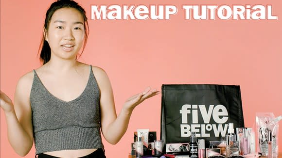 Young woman holding forearms up next to table with various cosmetics and a Five Below bag.