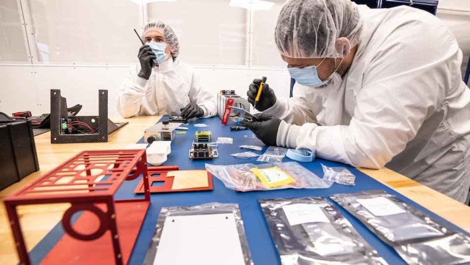 Chris Hays and Daniel Posada, left, assemble the EagleCam cubesat in the Space Technologies Lab clean room on July 29, 2021. The camera ics designed to operate in the harsh environment of space and will be installed and will generate images of a lunar landing.