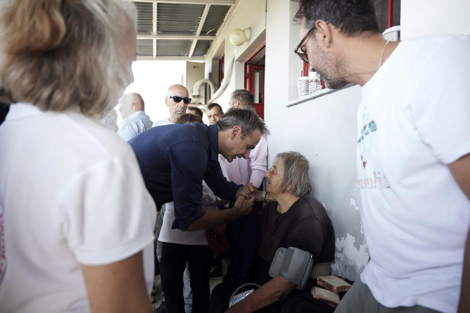In this photo provided by the Greek Prime Minister's Office, Greece's Prime Minister Kyriakos Mitsotakis speaks with an evacuee, from a flooded village, at a soccer stadium, in Karditsa, Thessaly region, central Greece, on Friday, Sept. 8, 2023. Severe rainstorms eased but floodwaters were still rising in parts of central Greece Friday, while fire department and military helicopters were plucking people from villages inundated by tons of water and mud that have left several people dead and others missing and many people clinging to the roofs of their homes, appealing for rescue. (Dimitris Papamitsos/Greek Prime Minister's Office via AP)