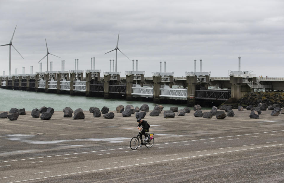 A competitor battles gale force winds during the Dutch Headwind Cycling Championships on the storm barrier Oosterscheldekering, rear, near Neeltje Jans, south-western Netherlands, Sunday, Feb. 9, 2020. (AP Photo/Peter Dejong)