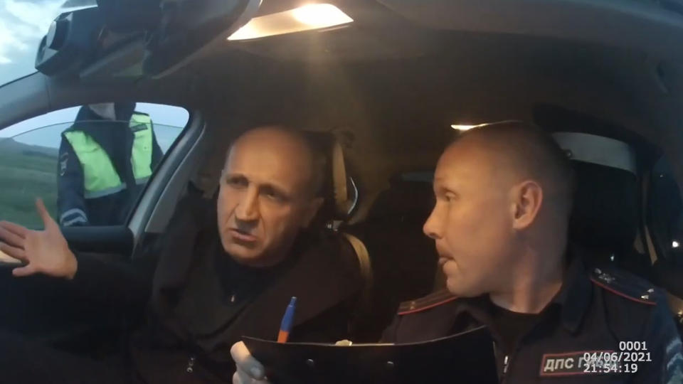 A suspected drunk driver speaks with a police officer in the Irkutsk region in Russia on June 4, 2021.