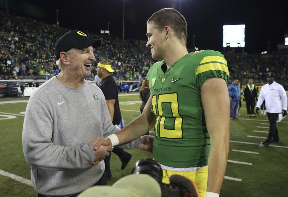 On the sideline, Oregon defensive coordinator Jim Leavitt shakes hands with Justin Herbert.