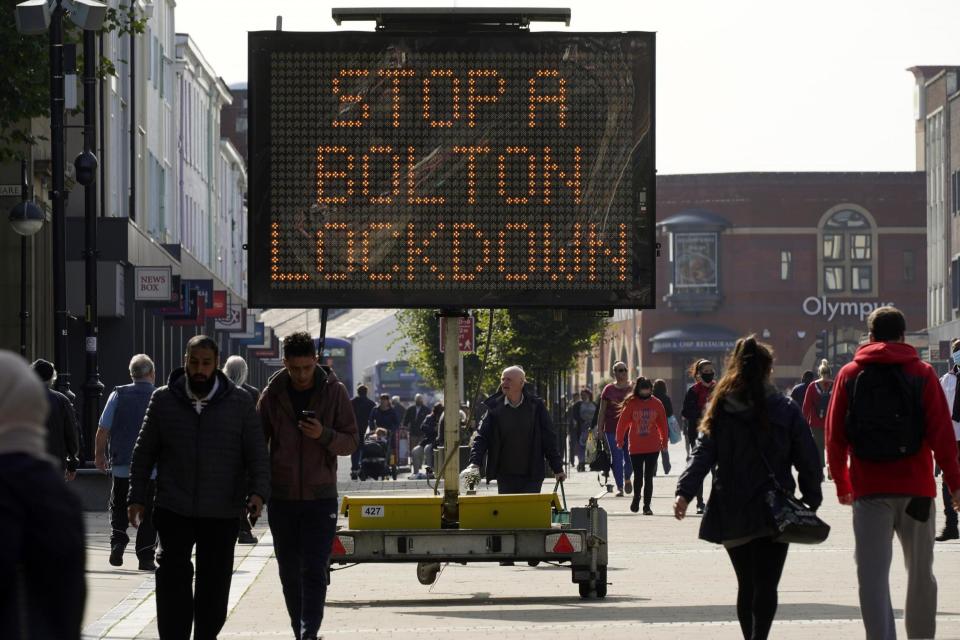 People walk past an electronic sign displaying health advice about Covid-19 in Bolton (file photo) (Getty Images)