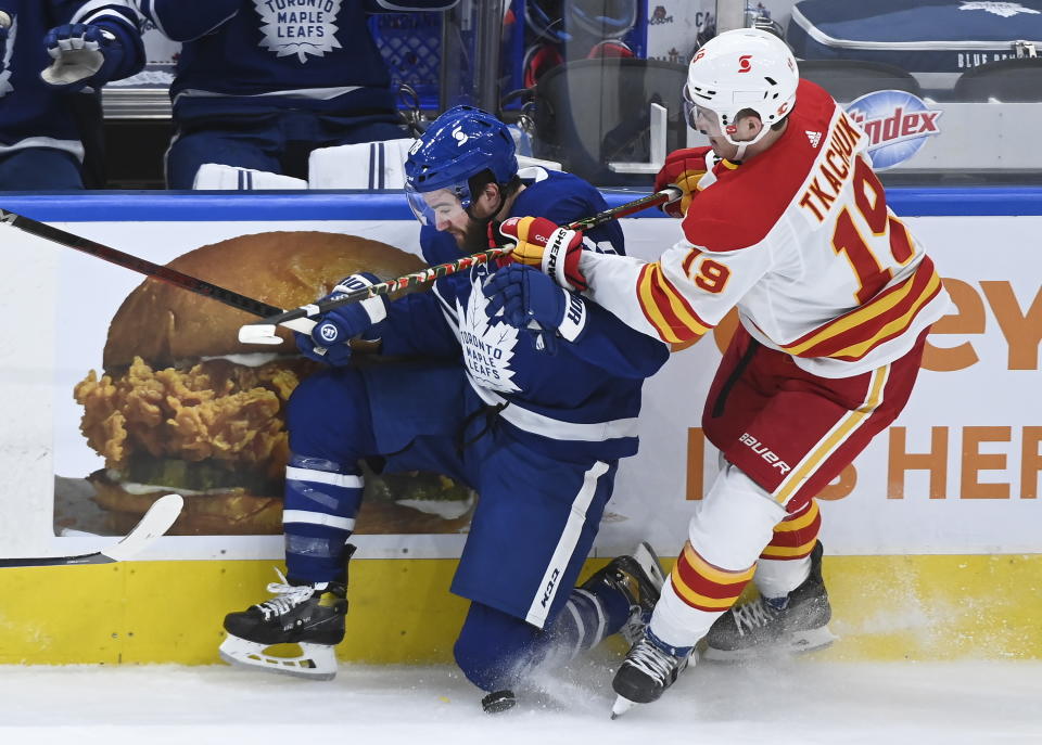 Calgary Flames left wing Matthew Tkachuk (19) takes out Toronto Maple Leafs defenseman TJ Brodie (78) during first-period NHL hockey game action in Toronto, Monday, Feb. 22, 2021. (Nathan Denette/The Canadian Press via AP)