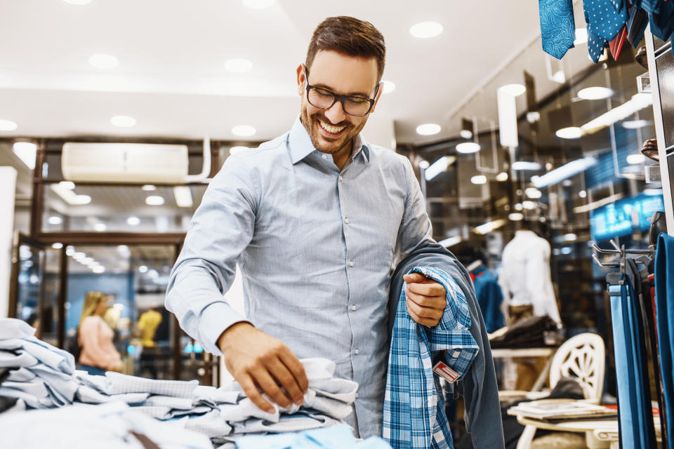 A man happily shopping for clothes in a clothing store