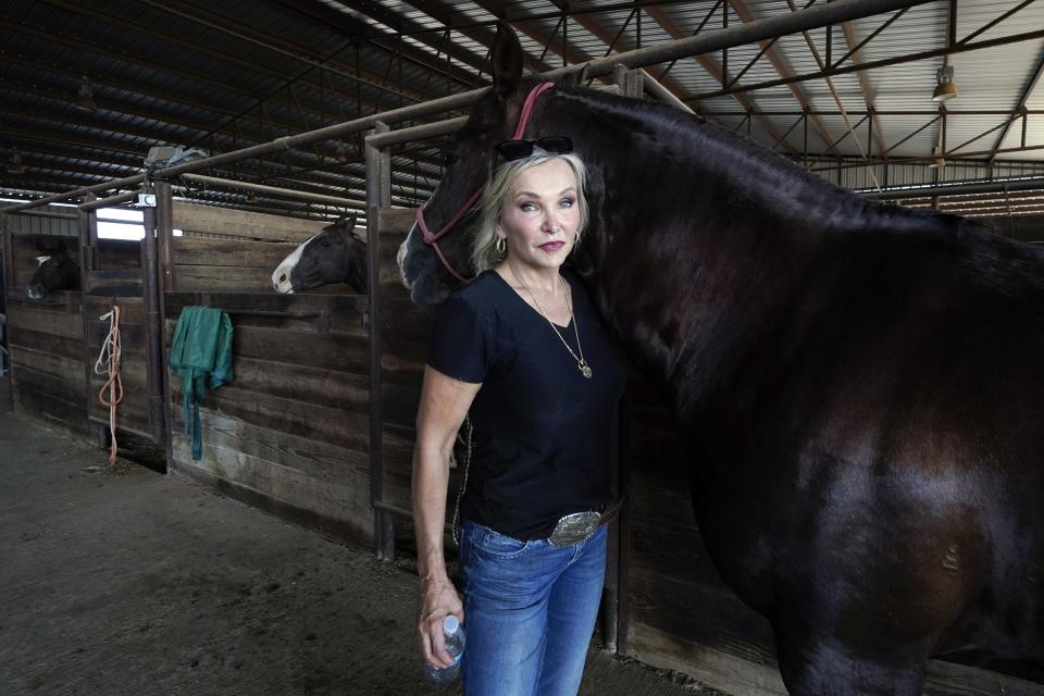 Ranch owner Gilda Jackson poses for a photo as she works with one of her horses in the arena on her property in Paradise, Texas, Monday, Aug. 21, 2022. The Texas ranch where Jackson trains and sells horses has been plagued by grasshoppers this year, a problem that only gets worse when the hatch quickens in times of heat and drought. Jackson watched this summer as the insects chewed through a 35-acre pasture she badly needs for hay and what they didn't destroy, the sun burned up. (AP Photo/Tony Gutierrez)