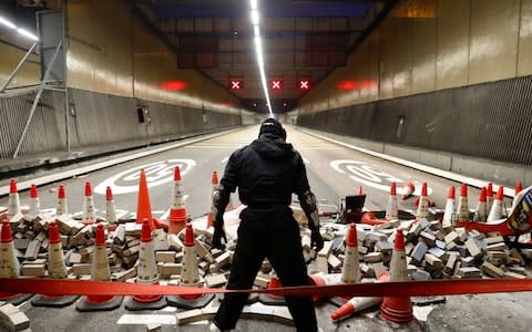 An anti-government protesters stands at a blocked outlet of the Cross Harbour Tunnel near the Polytechnic University in Hong Kong - Credit: Reuters