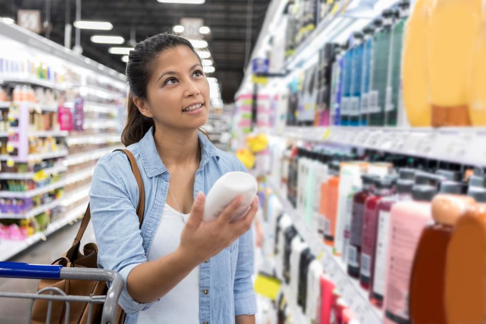 Woman shopping for conditioner at the supermarket.
