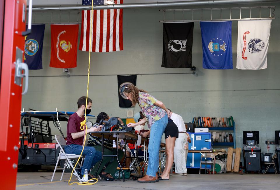 Poll workers check in voters as they prepare to cast their ballots at a polling station setup in a fire station on August 23, 2022 in Miami Beach, Florida.