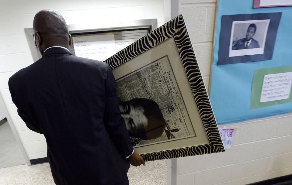 A man walks out of the gymnasium with a picture of Nelson Mandela following a ceremony at Nelson Mandela Park Public School in Toronto, December 6, 2013. Students, staff and school board officials gathered at the school to pay tribute to Mandela with songs and tributes. Mandela visited the school, which was previously known as Park Public, on November 17, 2001, when it was renamed in his honour. South African anti-apartheid hero Mandela died at the age of 95 on Thursday. REUTERS/Aaron Harris (CANADA - Tags: EDUCATION POLITICS OBITUARY)