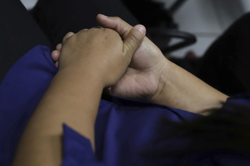 Evelyn Beatriz Hernandez folds her hands in her lap during her second trial, after her 30-year sentence for murder was overturned in February, in Ciudad Delgado on the outskirts of San Salvador, El Salvador, Monday, July 15, 2019. The young woman who was prosecuted under the country's highly restrictive abortion laws after birthing a baby into a pit latrine says she had no idea she was pregnant, as a result of a rape. (AP Photo/Salvador Melendez)