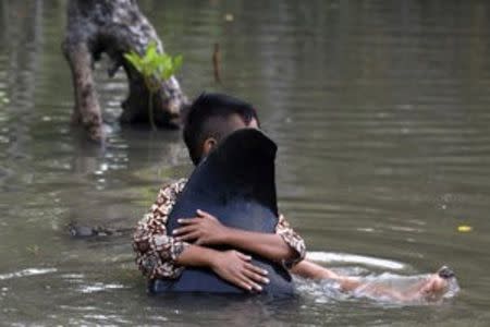 A child hugs a fin of a dead whale stranded on the coast of Pesisir beach in Probolinggo, Indonesia, June 16, 2016. Antara Foto/Zabur Karuru/via REUTERS