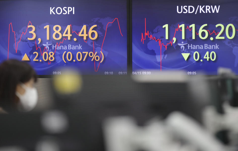 A currency trader walks by the screens showing the Korea Composite Stock Price Index (KOSPI), left, and the foreign exchange rate between U.S. dollar and South Korean won at the foreign exchange dealing room in Seoul, South Korea, Thursday, April 15, 2021. Asian stock markets were mixed Thursday after Wall Street retreated from a record high as major banks reported strong profits at the start of U.S. earnings season. (AP Photo/Lee Jin-man)