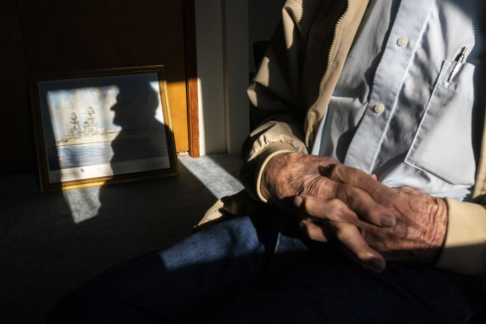 Pearl Harbor survivor and World War II Navy veteran David Russell, 101, poses for a press photo along with a painting of the USS Oklahoma at his home on Monday, Nov. 22, 2021, in Albany, Ore. (AP Photo/Nathan Howard)