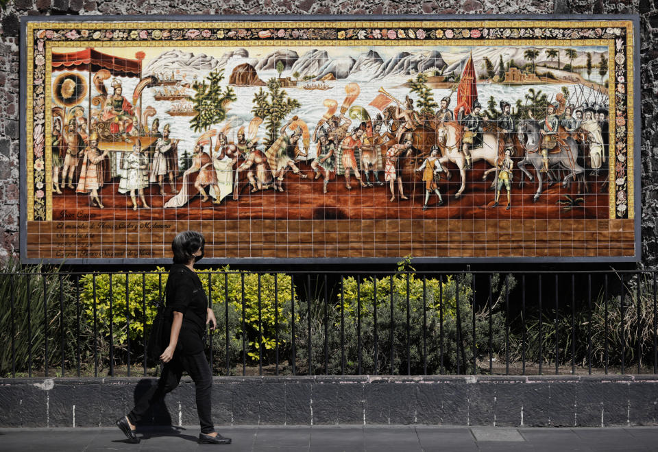 A woman walks past a mural commemorating the meeting of the Spanish conquistador Hernan Cortes and the Aztec Emperor Moctezuma in Mexico City, Tuesday, May 18, 2021. The capital of the Aztec empire, now known as Mexico City, fell after a prolonged siege 500 years ago, marking one of the few times an organized Indigenous army under local command fought European colonizers to a standstill for months, and the final defeat helped set the template for much of the conquest and colonization that came afterward. (AP Photo/Eduardo Verdugo)