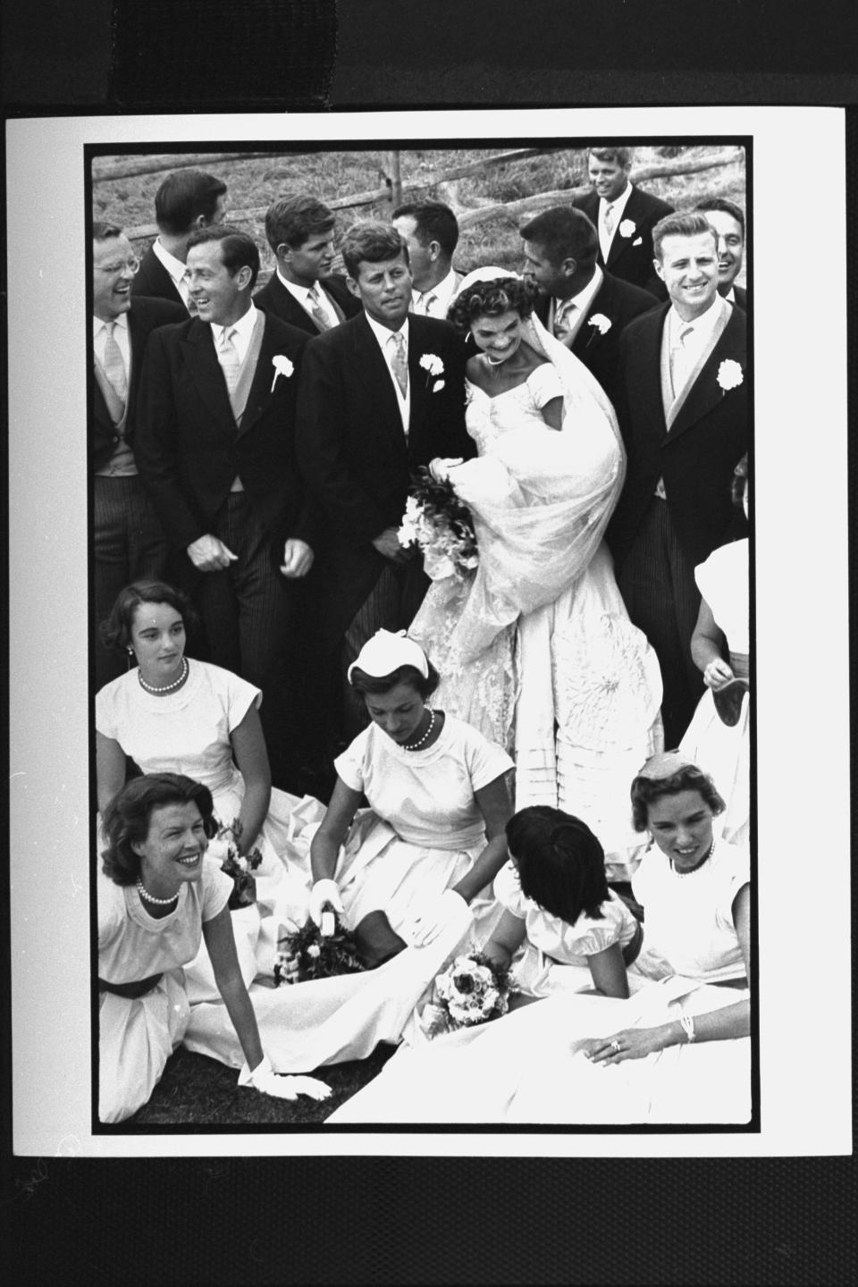 Sen. John Kennedy & his bride Jacqueline in their wedding attire, standing with 10 ushers incl. Teddy & Bobby Kennedy as 4 bridesmaids & flower girls sits on lawn in front of them while attempting to pose for group shot at their wedding. (Photo by Lisa Larsen//Time Life Pictures/Getty Images)