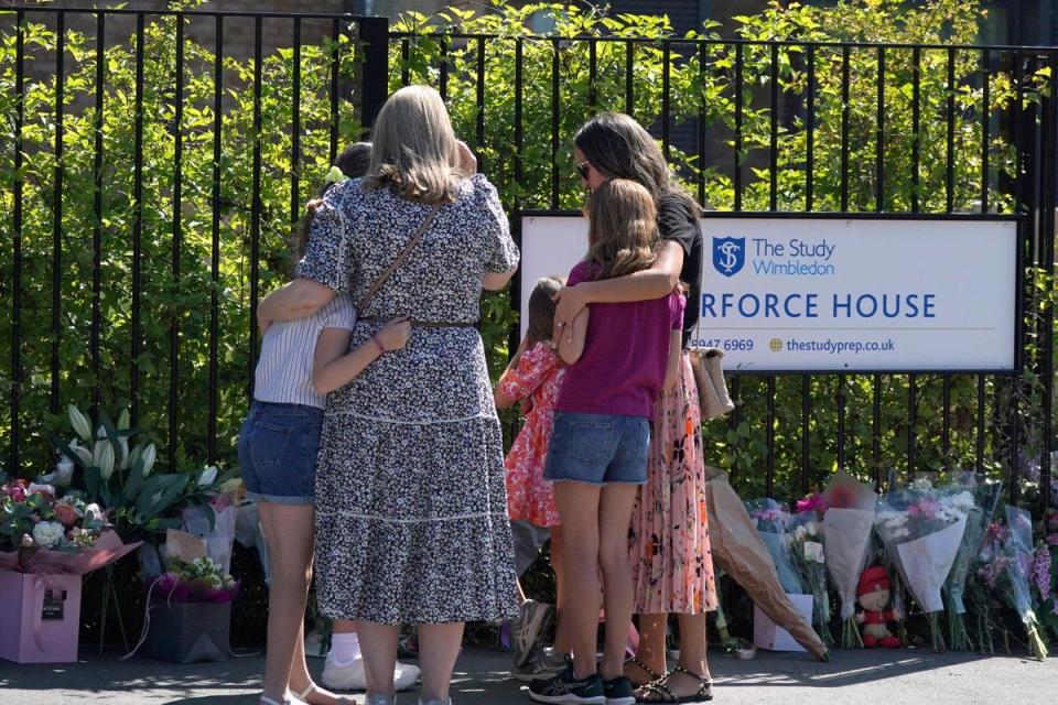 Two women with young girls look at flowers and messages left outside the Study Preparatory School in Wimbledon (PA Wire)