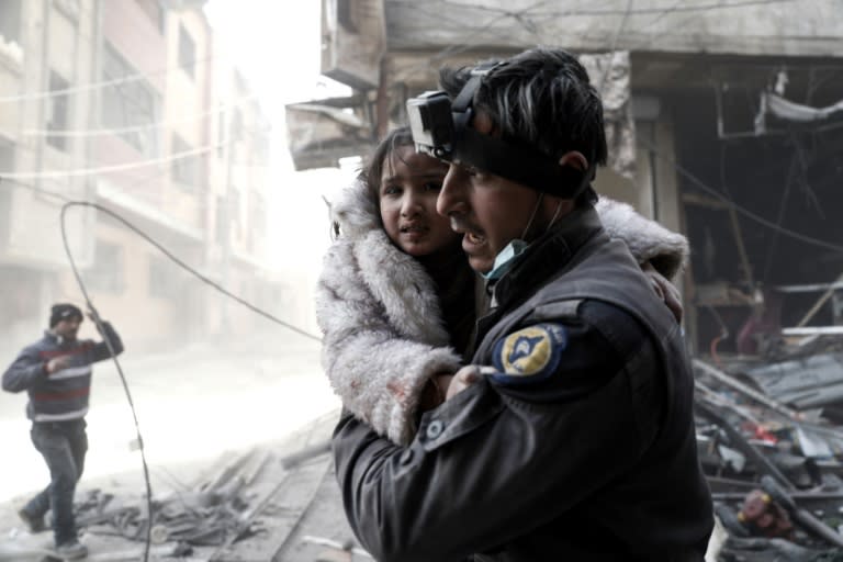 A Syrian White Helmets rescue worker carries a girl from the site of a government airstrike on the rebel-held town of Douma, on the eastern outskirts of Damascus, on February 25, 2017