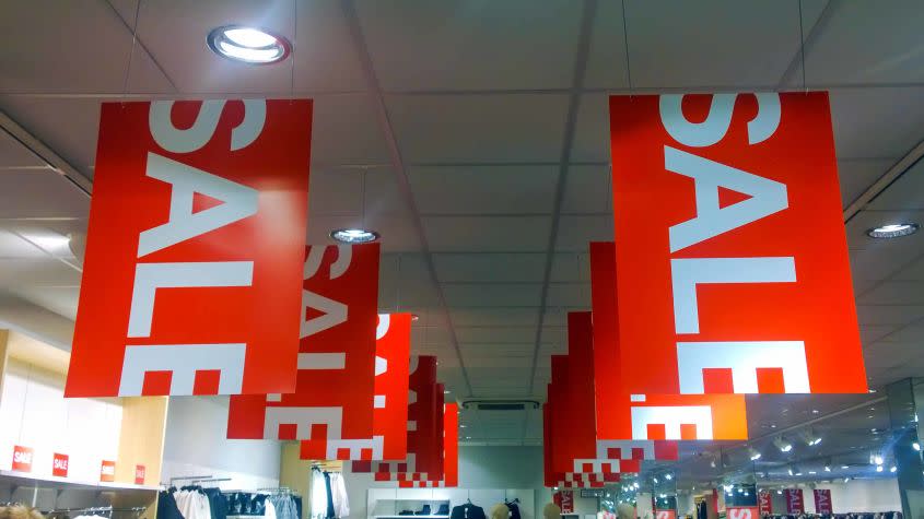 red sign with white &quot;sale&quot; letters hanging from store ceiling