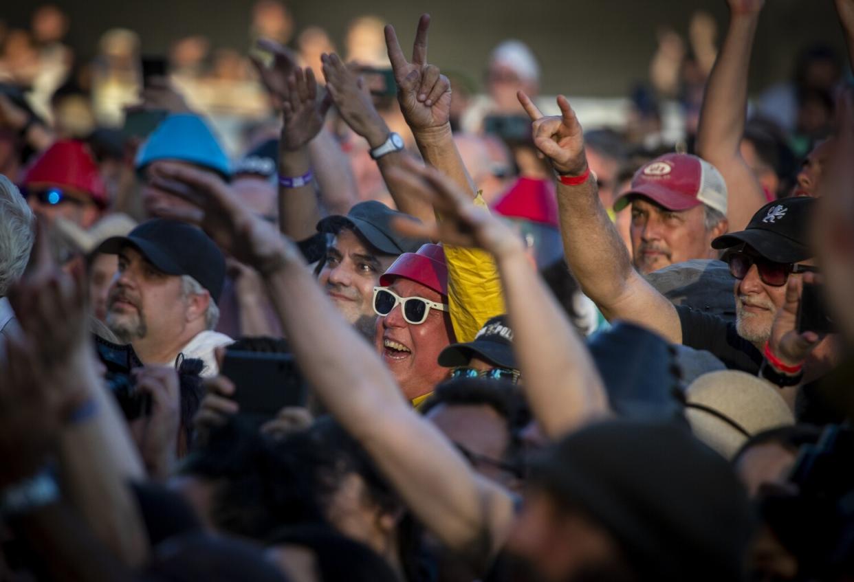 A fan wearing a red Devo hat joins others in the crowd cheering