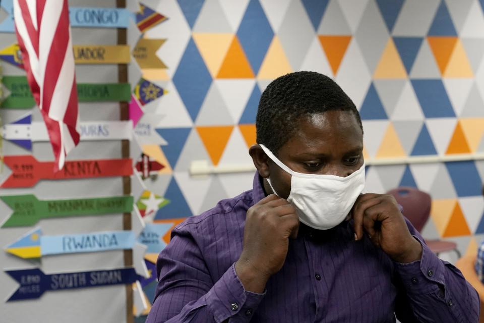 Teaching assistant Samuel Lavi adjusts his face covering at the Valencia Newcomer School, Tuesday, Sept. 2, 2020, in Phoenix. Communicating during the coronavirus pandemic has been trying for parents and students at the Phoenix school for refugees who speak a variety of languages and are learning to use technology like iPads and messaging apps. (AP Photo/Ross D. Franklin, Pool)
