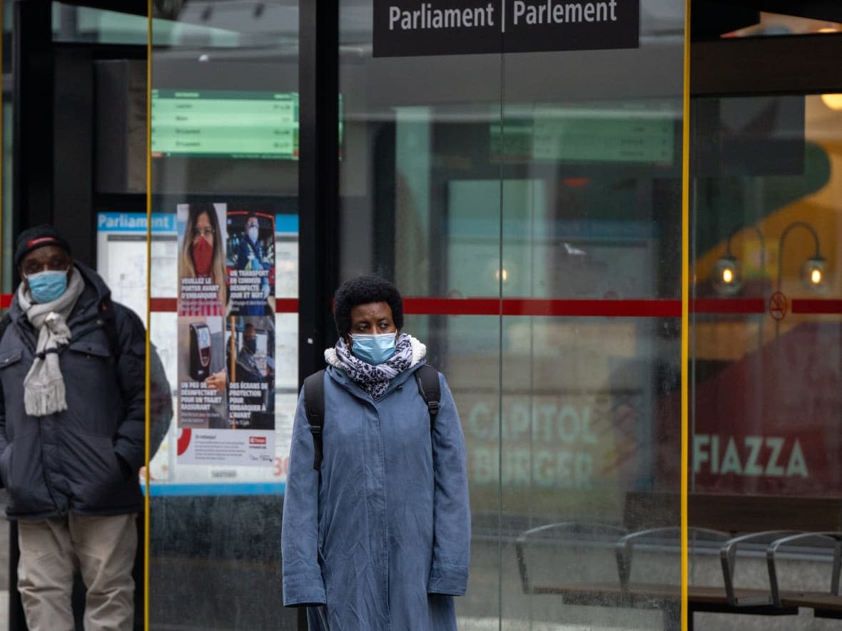 Two people wear masks as they wait for a bus to arrive outside the Parliament LRT station in downtown Ottawa. (Andrew Lee/CBC - image credit)