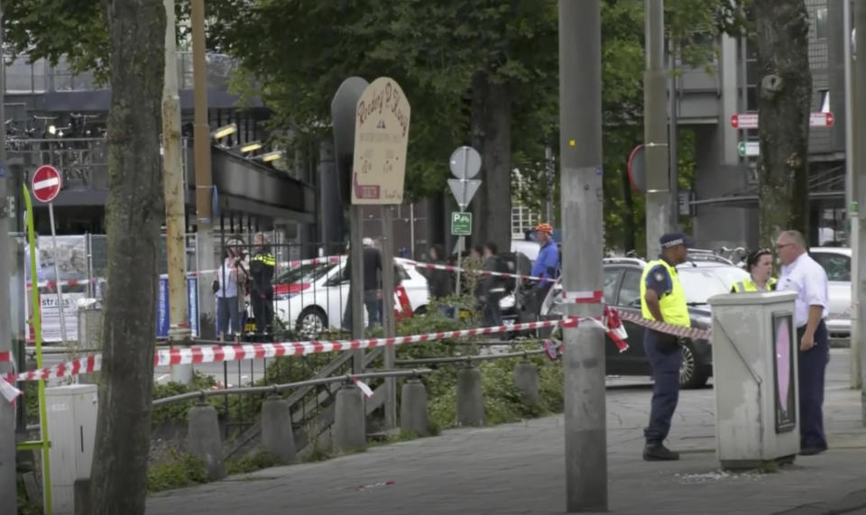 In this image made from video, Dutch police officers stand near the scene of a stabbing attack near the central daily station in Amsterdam, the Netherlands, Friday Aug. 31, 2018. Police the Dutch capital shot and wounded a suspect Friday following a stabbing at the central railway station. Amsterdam police said in a series of tweets that two people were injured in the stabbing and the suspect was then shot by officers. (AP Photo/Alex Furtula)