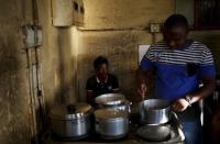 Zakhele Ntsele (R) cooks in a communal kitchen at Jeppestown men's hostel in Johannesburg May 19, 2015. REUTERS/Siphiwe Sibeko