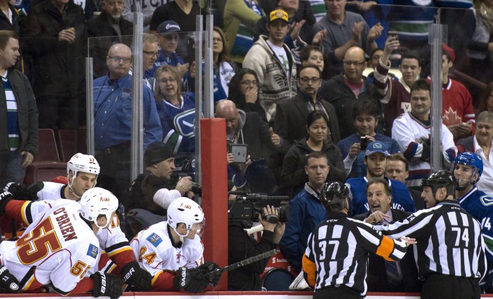 Referees get in the way of Vancouver Canucks head coach John Tortorella as he screams at the Calgary Flames bench during first period NHL hockey action at Rogers Arena in Vancouver, British Columbia Saturday Jan. 18, 2014. (AP Photo/The Canadian Press, Jonathan Hayward)