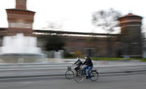 People wearing protective mask ride their bicycle at the Castello Sforzesco castle in Milan, Italy, Thursday, March 19, 2020.For most people, the new coronavirus causes only mild or moderate symptoms. For some it can cause more severe illness, especially in older adults and people with existing health problems. (AP Photo/Antonio Calanni)