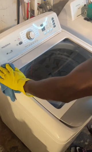 Person cleaning a top-load washing machine
