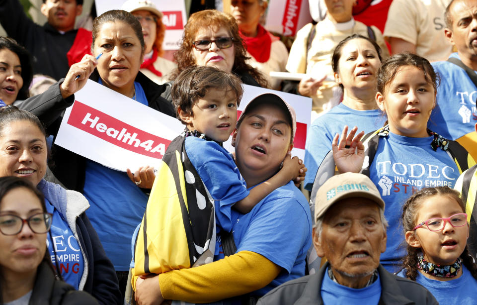FILE - In this May 20, 2019, file photo, Oralia Sandoval, center, holds her son Benjamin, 6, as she participates in an Immigrants Day of Action rally in Sacramento, Calif. California will become the first state to pay for some adults living in the country illegally to have full health benefits as the solidly liberal bastion continues to distance itself from President Donald Trump's administration. (AP Photo/Rich Pedroncelli, File)