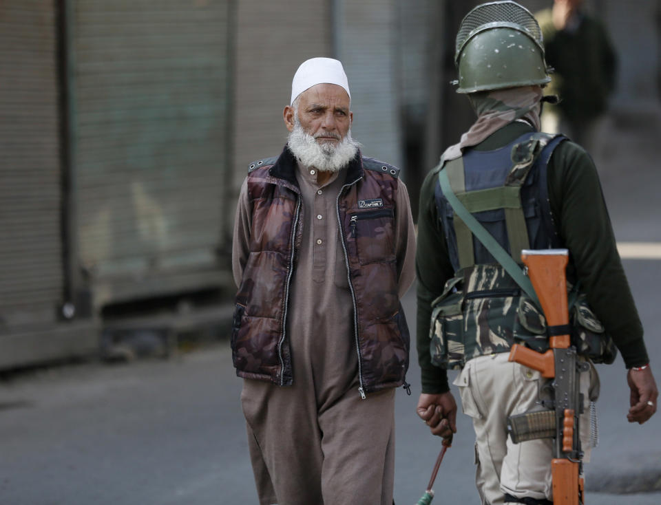 An elderly Kashmiri man walks past an Indian paramilitary soldier in Srinagar, Indian controlled Kashmir, Monday, Oct. 22, 2018. Armed soldiers and police have fanned out across much of Indian-controlled Kashmir as separatists challenging Indian rule called for a general strike to mourn the deaths of civilians and armed rebels during confrontation with government forces. (AP Photo/Mukhtar Khan)