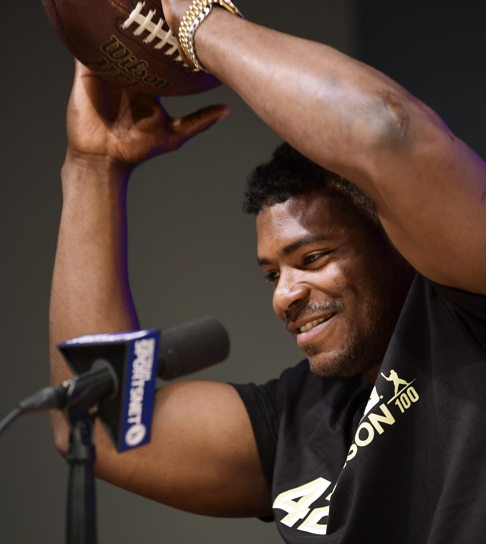 Cincinnati Reds' Yasiel Puig catches a football thrown by Los Angeles Dodgers relief pitcher Kenley Jansen as he speaks to reporters prior to a baseball game between the Dodgers and the Reds, Monday, April 15, 2019, in Los Angeles. (AP Photo/Mark J. Terrill)