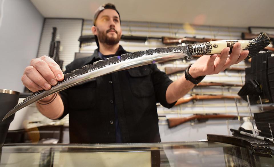 Owner Michael O'Reagan holds an Afghanistan Khyber Pass sword at Collectable Firearms & Militaria on Rhode Island in Fall River.