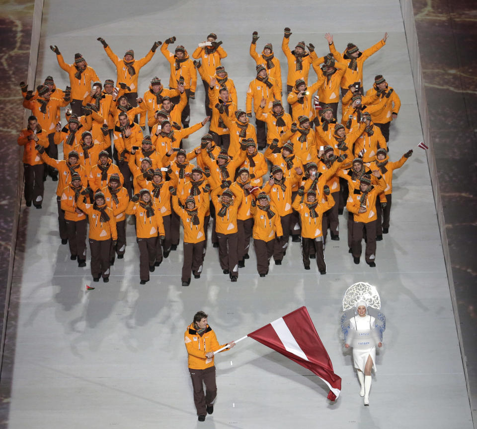 Sandis Ozolins of Latvia holds his national flag and enters the arena with teammates during the opening ceremony of the 2014 Winter Olympics in Sochi, Russia, Friday, Feb. 7, 2014. (AP Photo/Charlie Riedel)