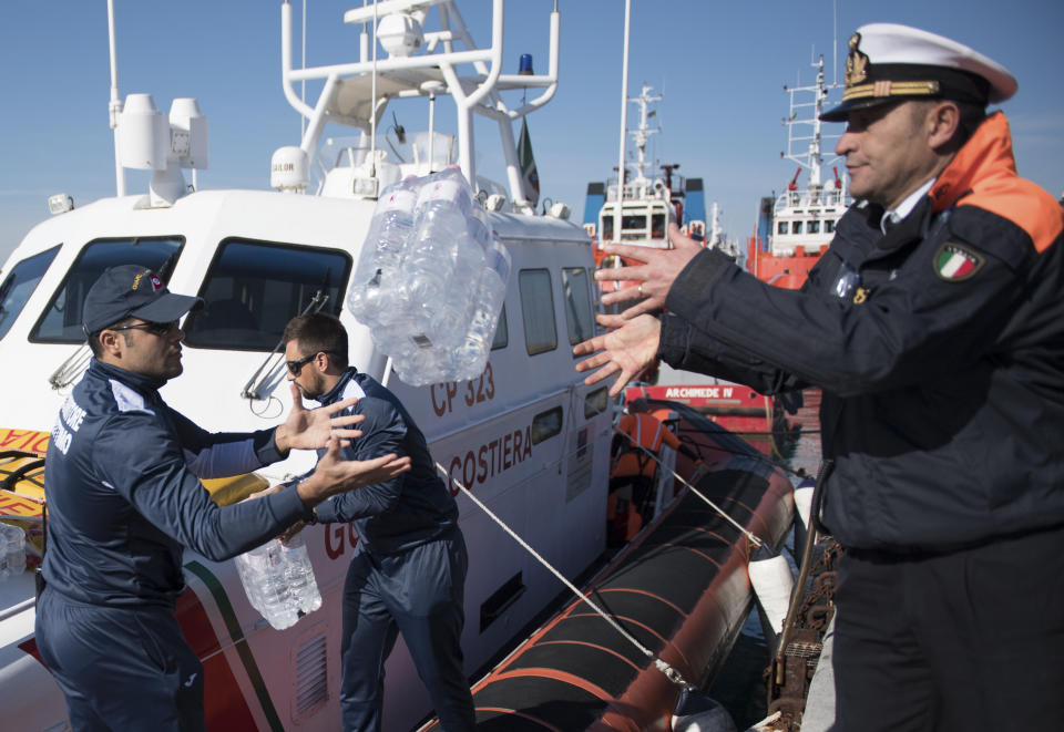 Water is unloaded from a coastguard boat to the German humanitarian group's rescue boat Sea Watch 3, as food and blankets for the cold were delivered, off the coast of Syracuse, Italy, Sunday, Jan. 27, 2019. The Italian coast guard is bringing socks, shoes, bread and fruit to 47 migrants who have been stranded at sea for nine days aboard a German ship. (AP Photo/Salvatore Cavalli)